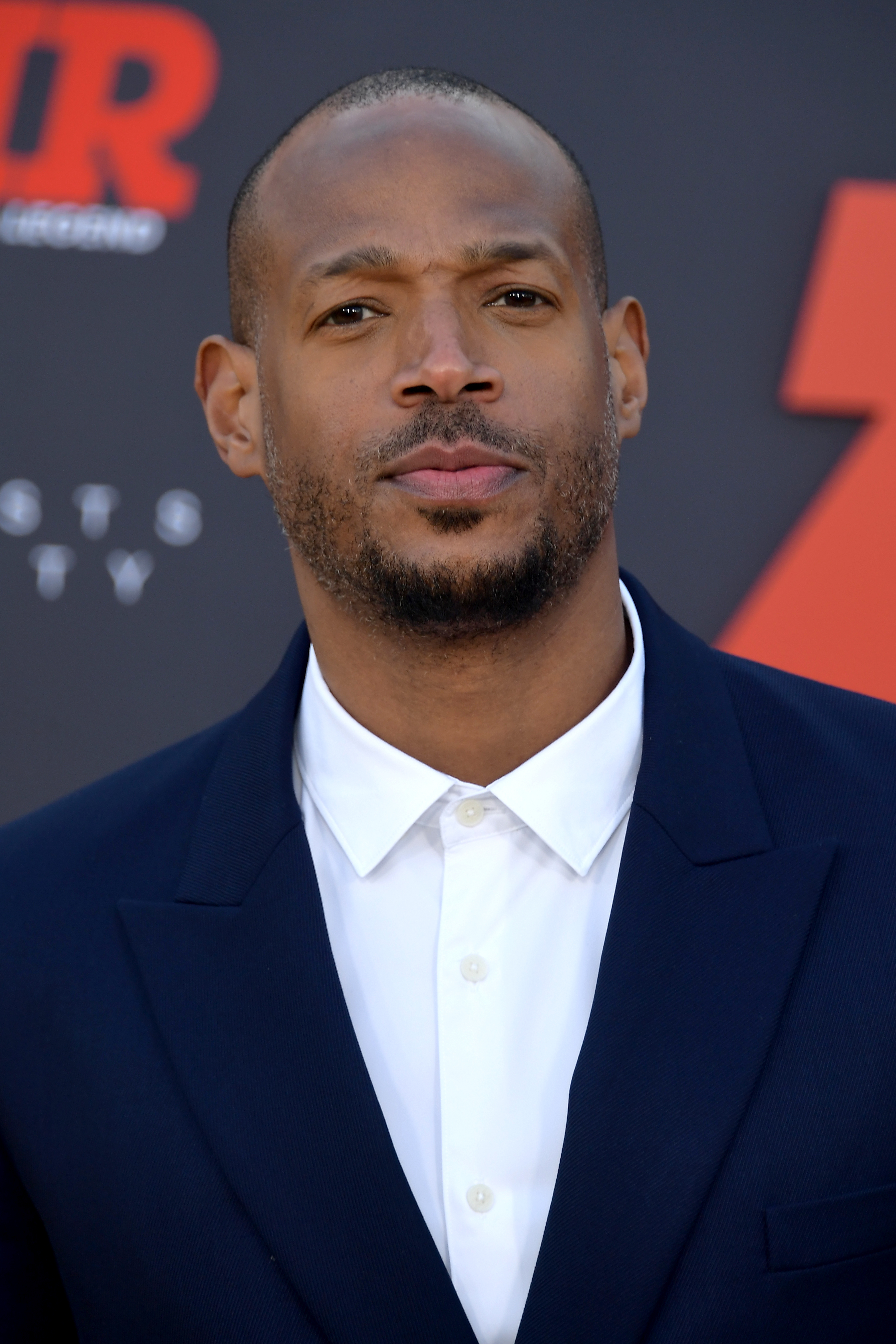 Marlon Wayans attends a red carpet event, wearing a white shirt under a dark blazer