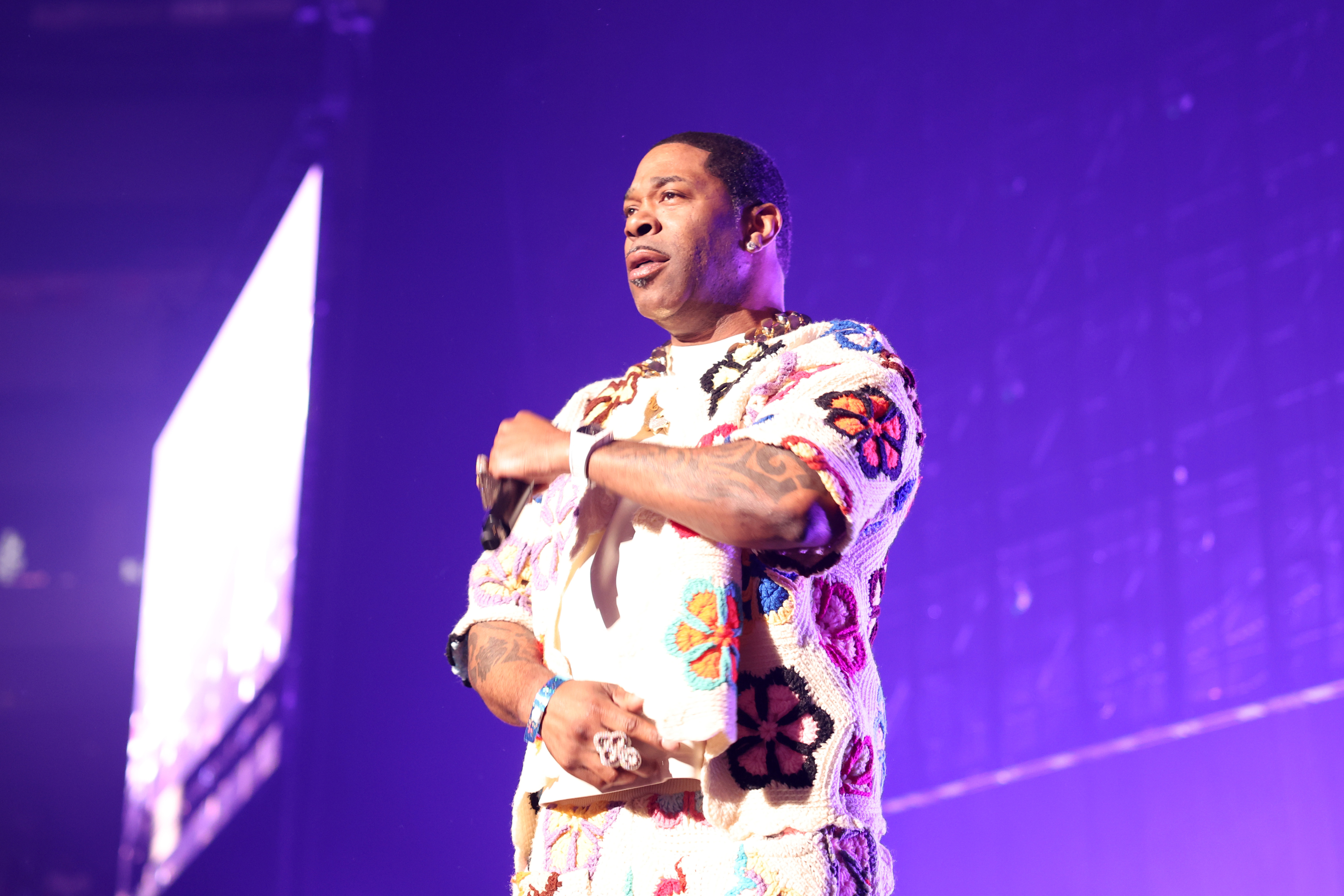 Busta Rhymes performing on stage, wearing a matching short-sleeved top and pants with a floral pattern