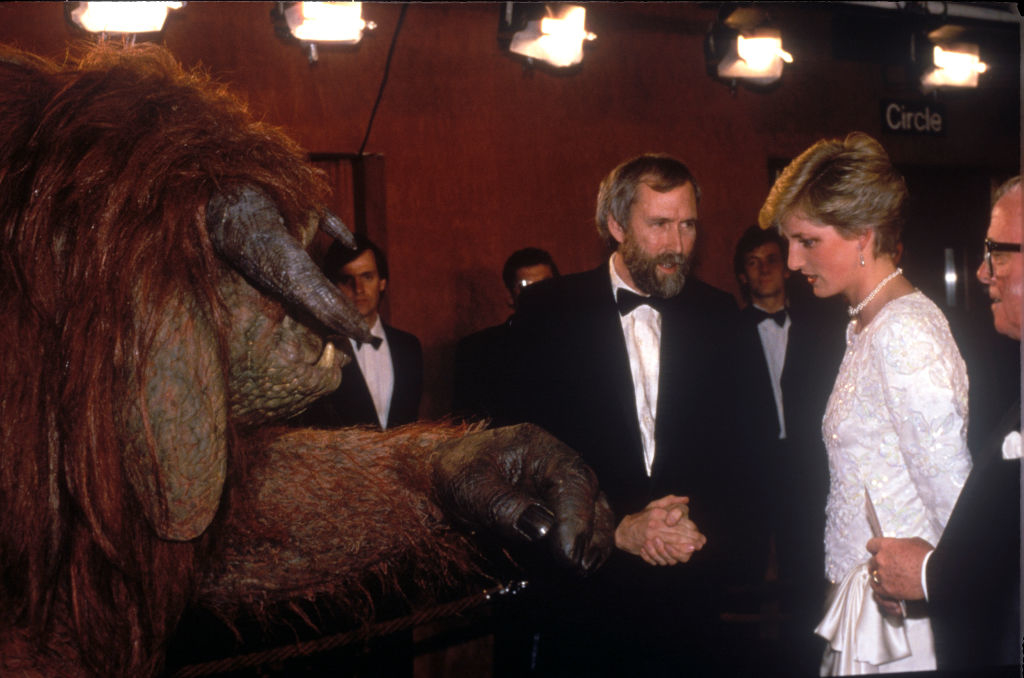 Jim Henson, Princess Diana, and others talk at an event. Jim Henson interacts with a Labyrinth character in an elaborate costume