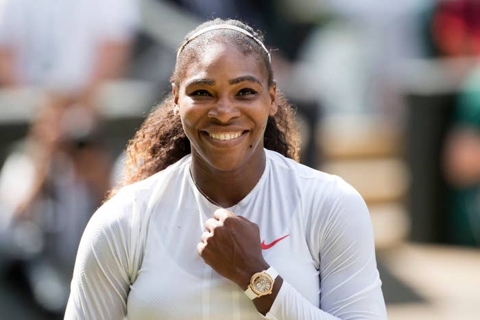 Serena Williams smiling, wearing a long-sleeve athletic top and a watch, with her hair pulled back