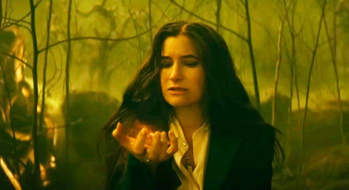 Kathryn Hahn as Agatha Harkness holds a glowing object in the forest in a scene from &quot;Agatha All Along&quot;
