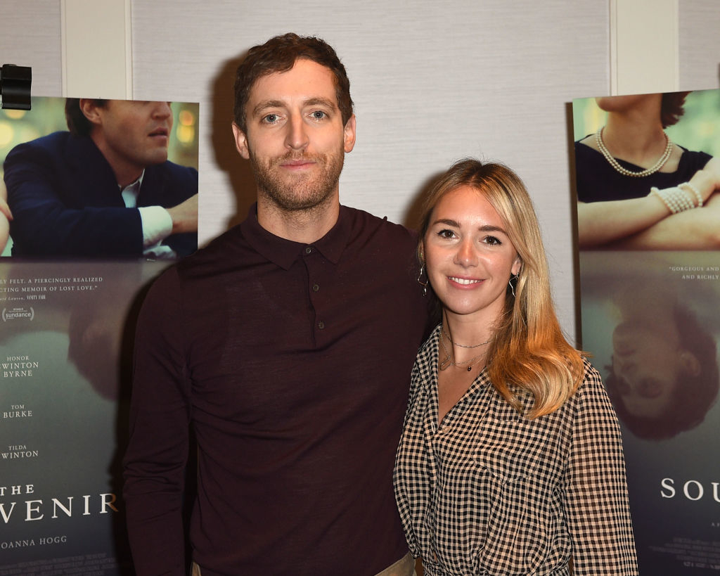 Thomas Middleditch and Mollie Gates stand together in front of movie posters at an event. Thomas wears a dark shirt, and Mollie wears a checkered blouse