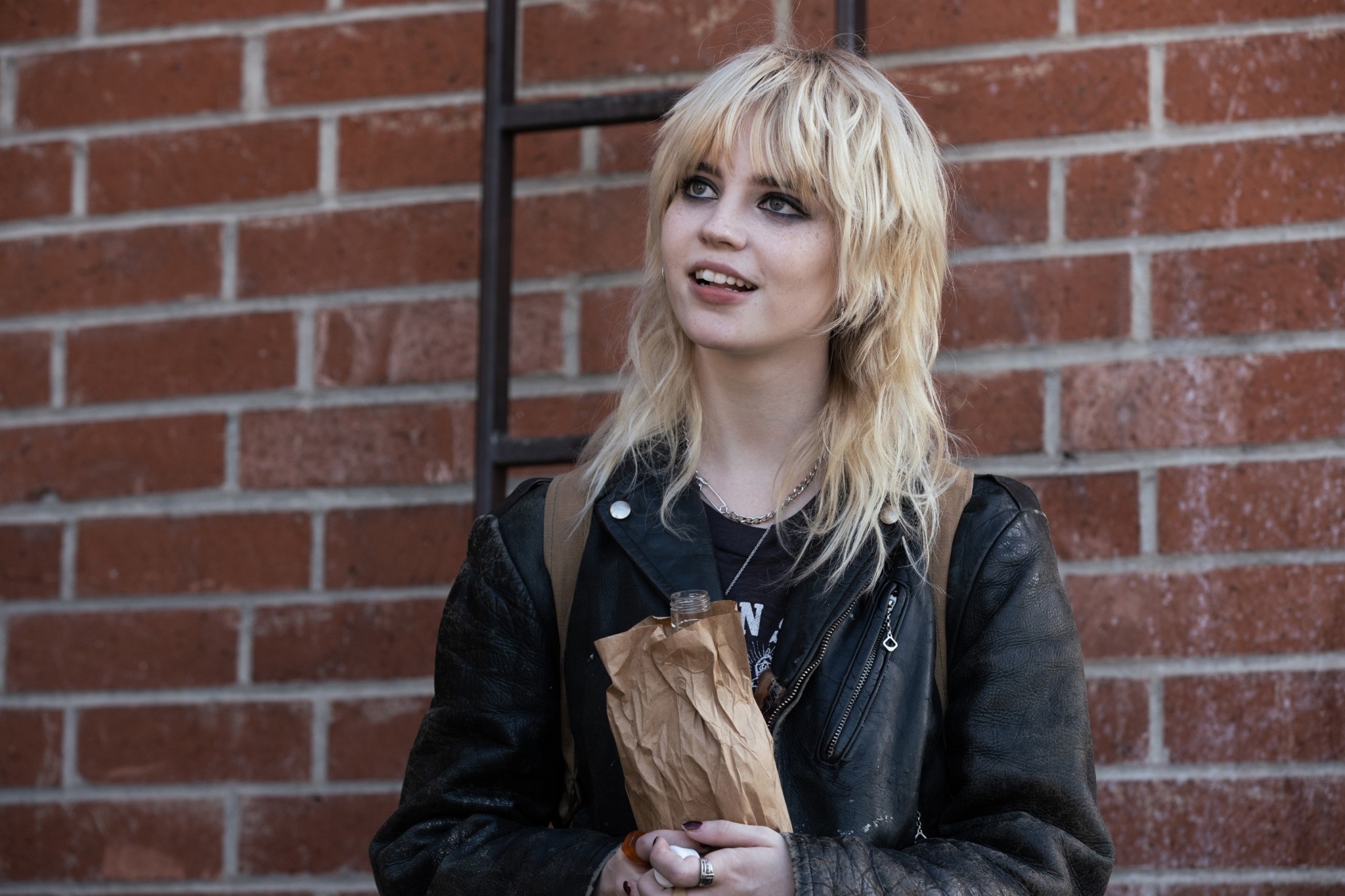 Sophie Thatcher with a shag haircut and leather jacket in front of a brick wall in a scene from &quot;Yellowjackets&quot;