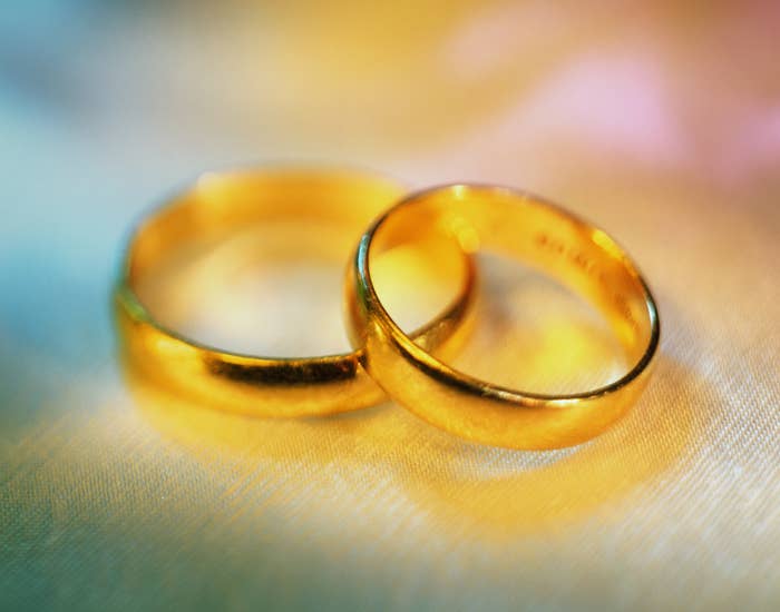 Two golden wedding bands resting closely together on a smooth surface