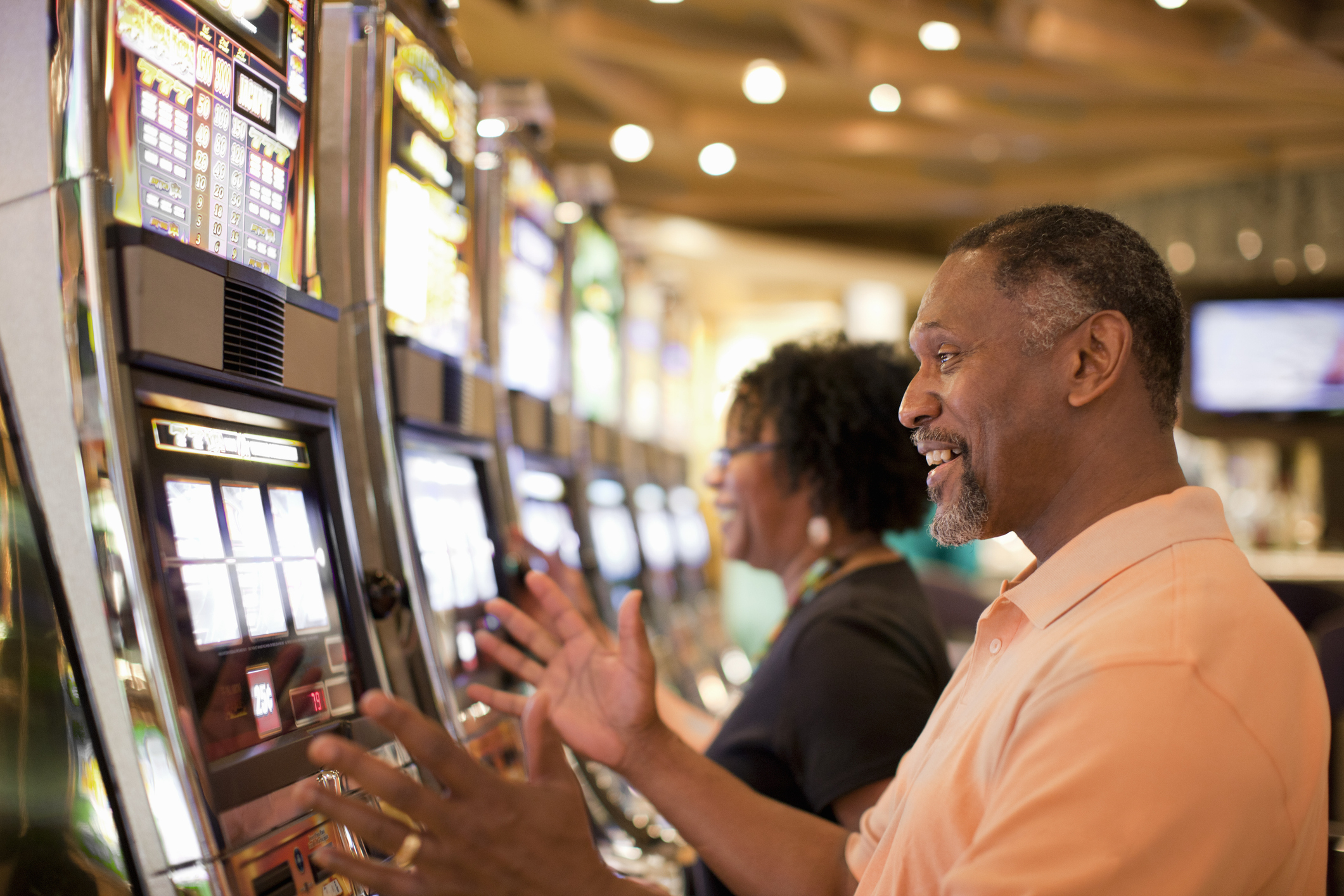 A man and a woman are enjoying themselves while playing slot machines in a casino