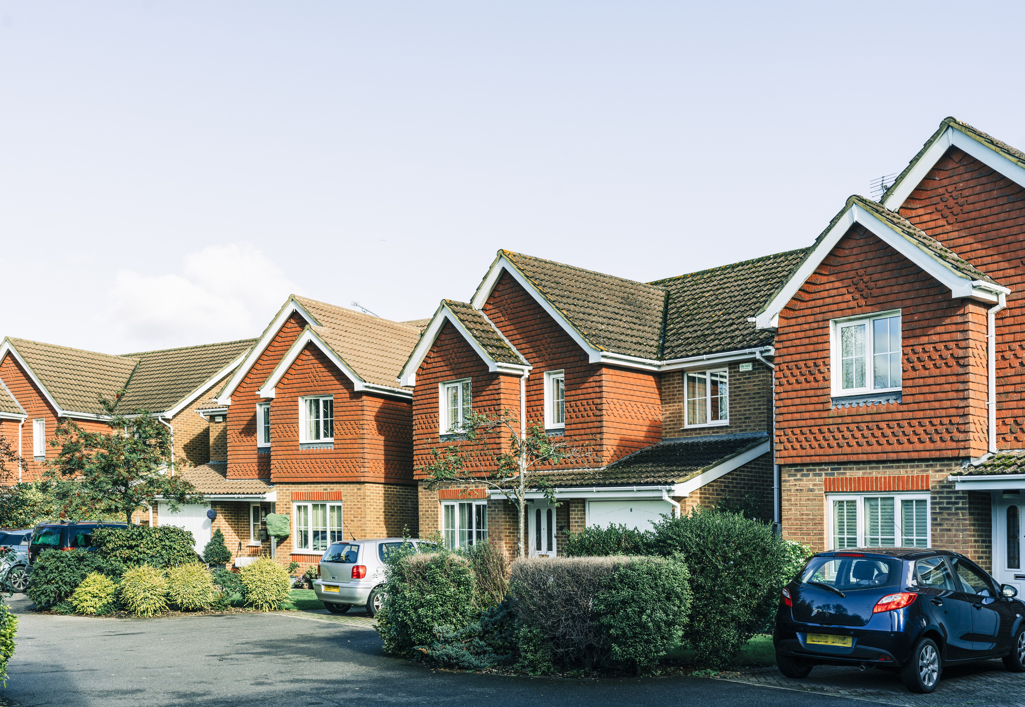 A row of suburban houses with manicured lawns and parked cars in the driveway. This image is used in an article categorized as Internet Finds