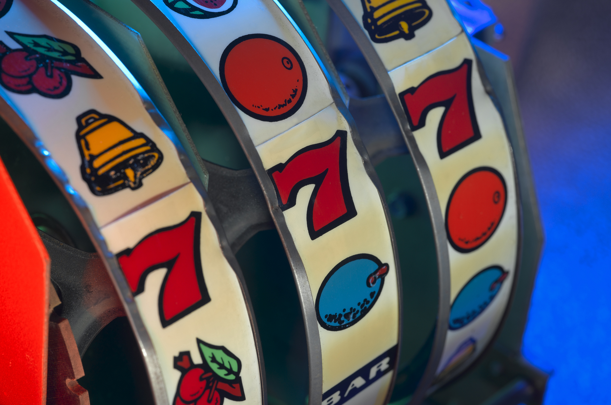 Close-up of a slot machine&#x27;s spinning reels displaying a combination of symbols including cherries, a bell, and the number seven