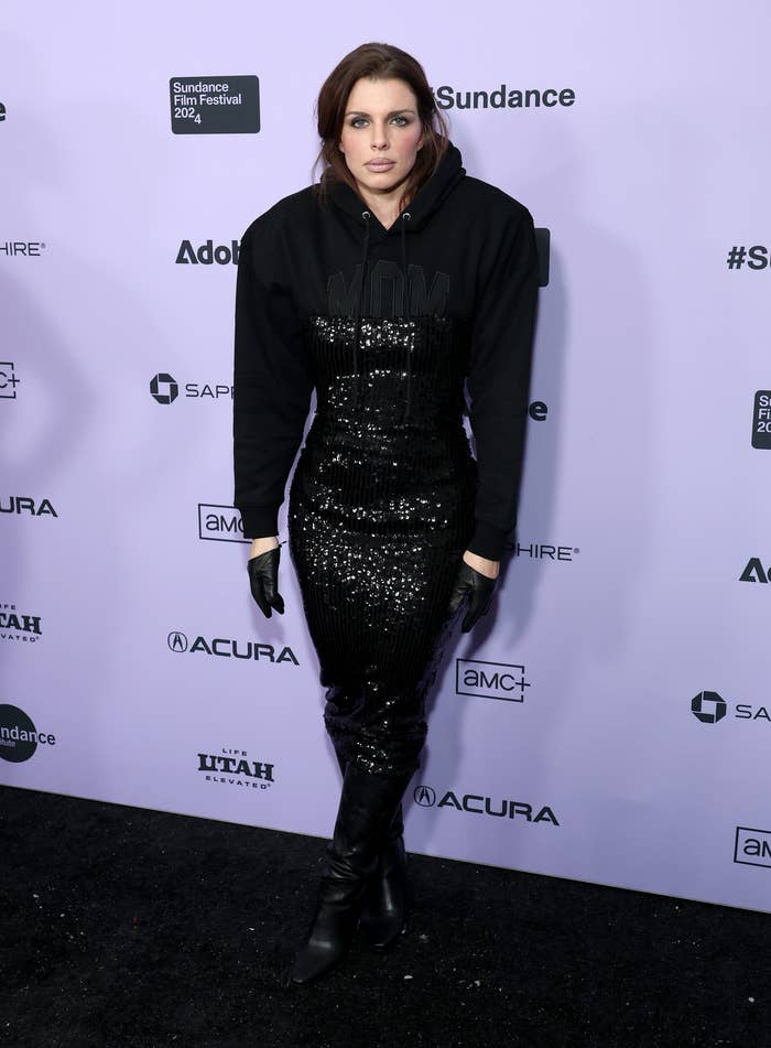 Julia Fox at Sundance Film Festival 2023, wearing a black sequin dress and a black hoodie with &quot;WOMAN&quot; written on it, along with black boots and gloves