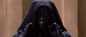 Darth Maul, a Star Wars character, stands in a hooded cloak, removing his hood to reveal his face