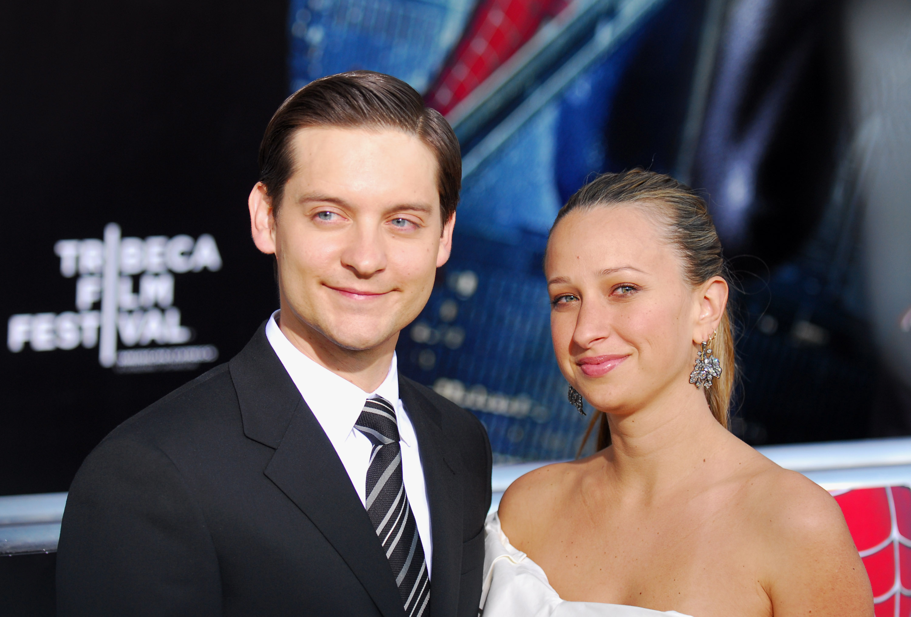 Tobey Maguire and Jennifer Meyer pose together at the Tribeca Film Festival in formal attire. Maguire wears a suit and tie, while Meyer wears a strapless dress