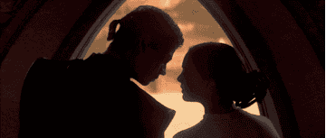 Anakin Skywalker and Padmé Amidala share a romantic moment standing closely together against a glowing backdrop in a scene from a Star Wars movie