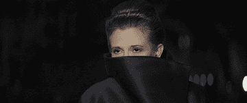 Carrie Fisher peeking over a large black collar, presumably on a red carpet