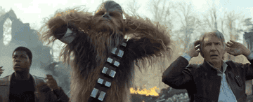 John Boyega, Chewbacca, and Harrison Ford in a dramatic scene from a Star Wars movie, appearing distressed with hands on heads