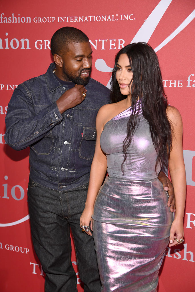Kanye West in a denim outfit and Kim Kardashian in a shiny metallic dress at a red carpet event