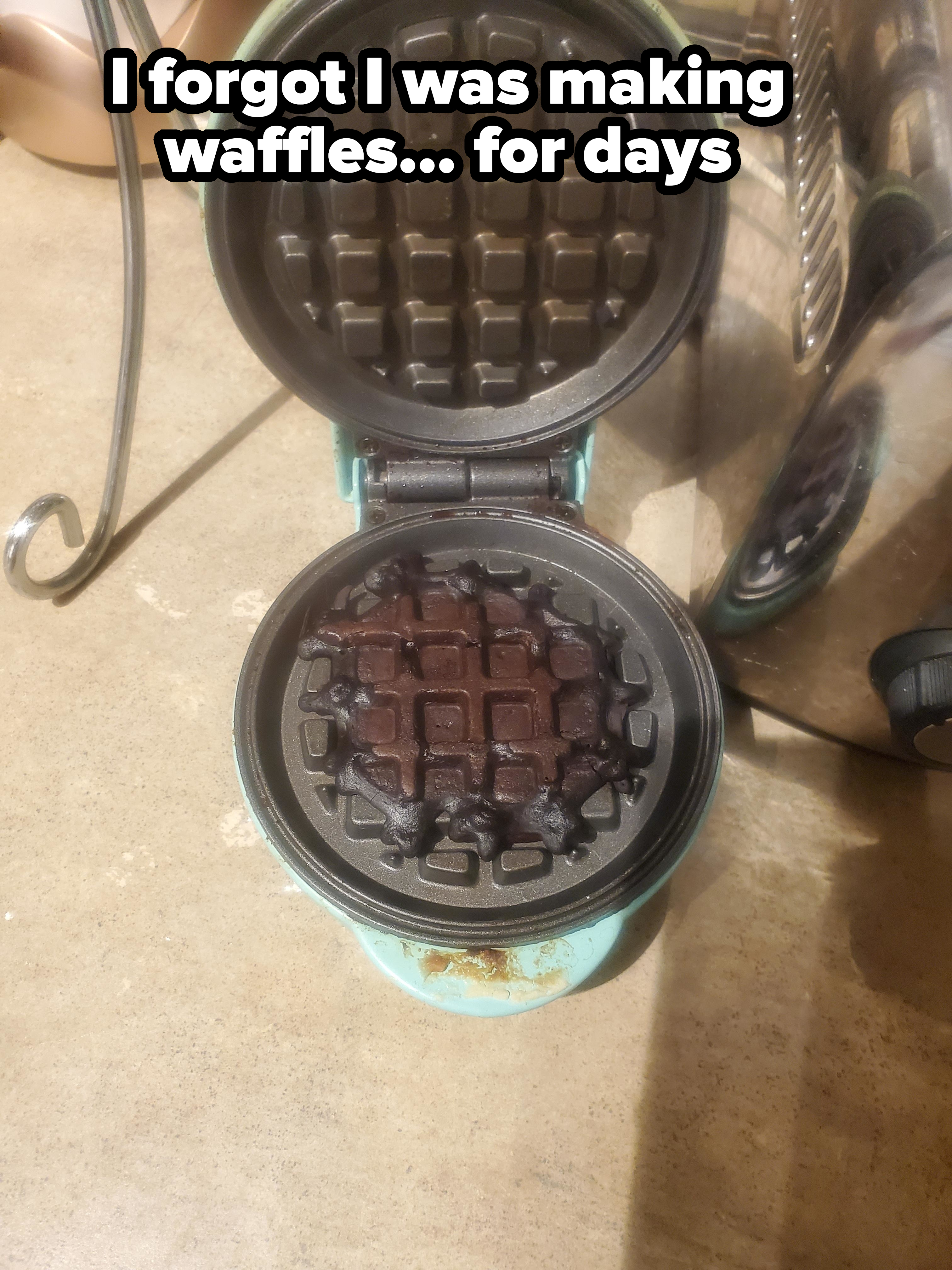 A waffle maker with a burnt waffle remains inside