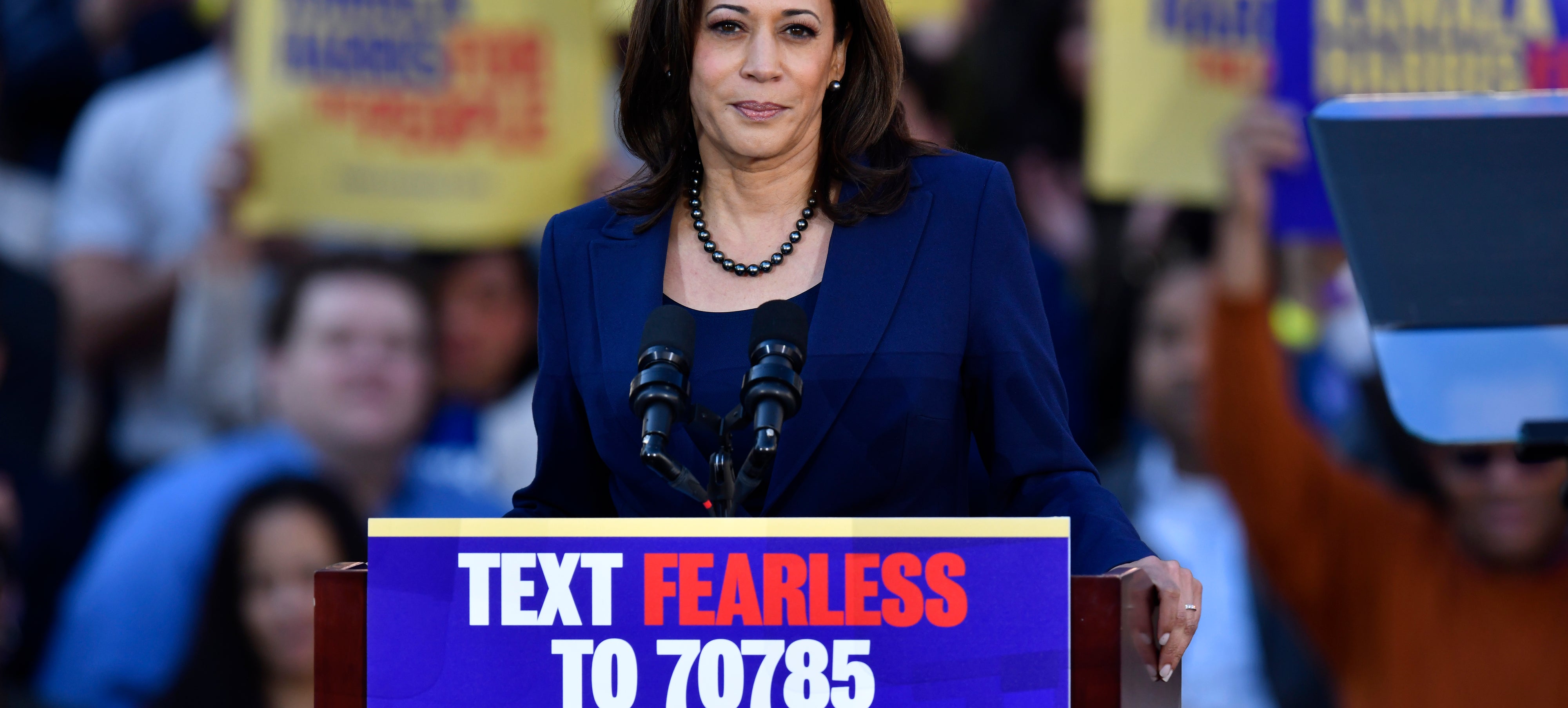 Kamala Harris speaking at an outdoor campaign event, standing behind a podium