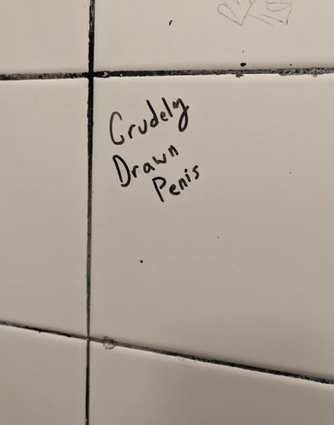 Graffiti on a tiled wall reads &quot;Crudely Drawn Penis.&quot;