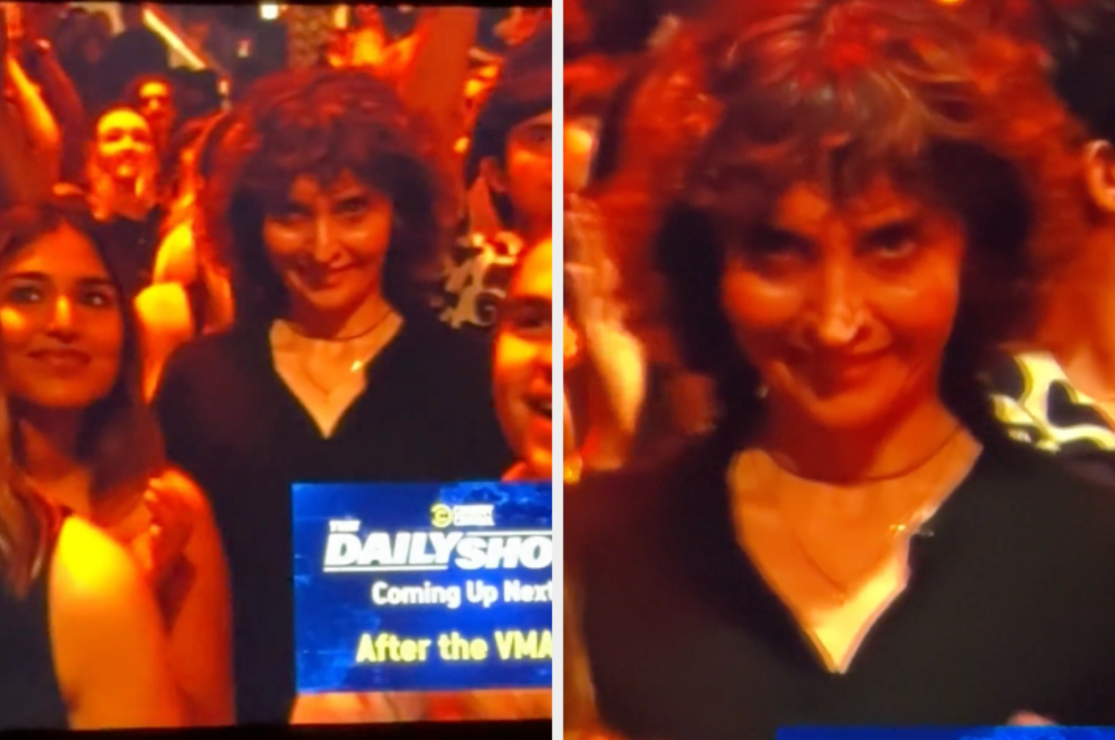 A woman with curly hair, standing among a crowd at an event, smiles directly at the camera. Text on screen: &quot;The Daily Show Coming Up Next After the VMAs&quot;