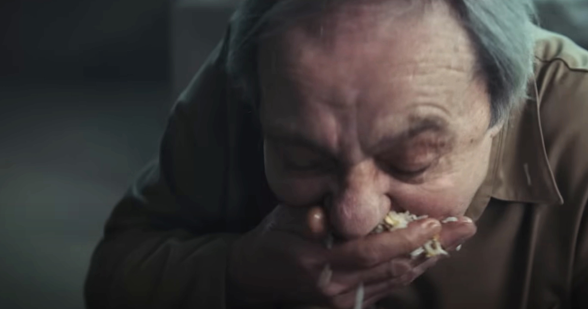 A person eating food messily with their hands directly from a container