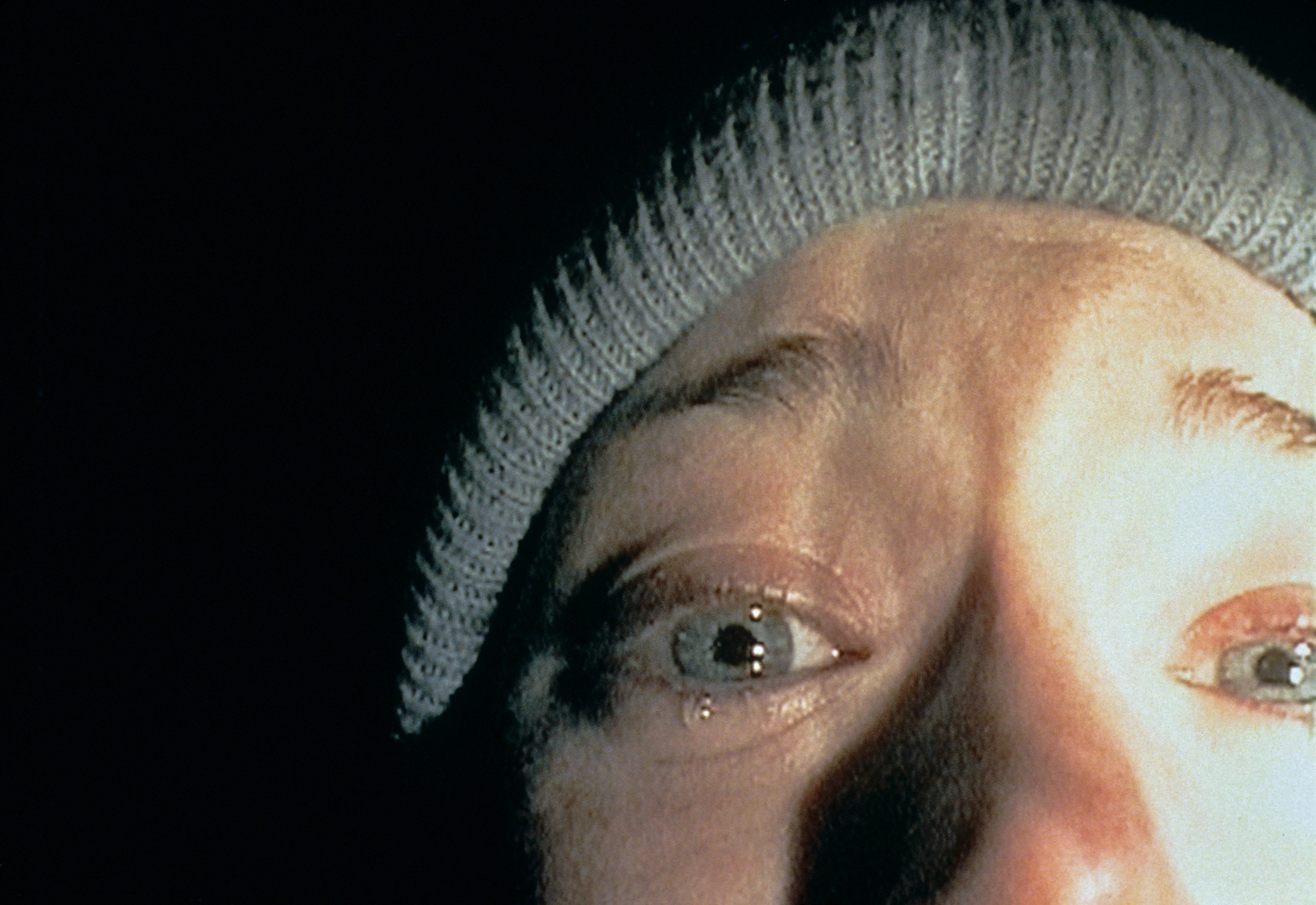 Close-up shot of Heather Donahue shedding a tear while wearing a beanie in &quot;The Blair Witch Project&quot;