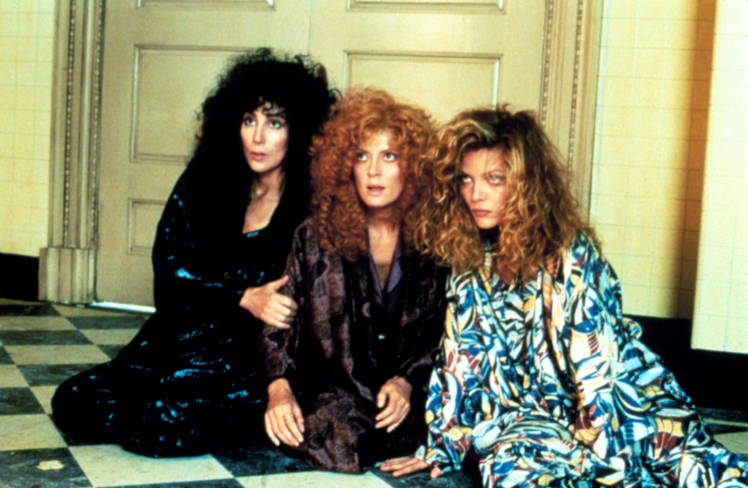 Cher, Susan Sarandon, and Michelle Pfeiffer sitting on the floor together in &quot;The Witches of Eastwick&quot;