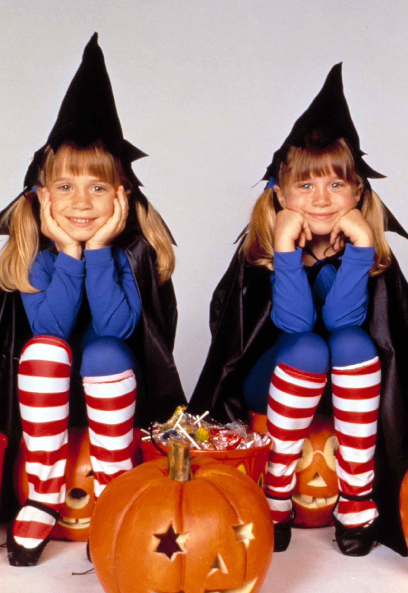 Mary-Kate and Ashley Olsen are dressed as witches with striped leggings, seated next to carved pumpkins in &quot;Double, Double, Toil and Trouble&quot;