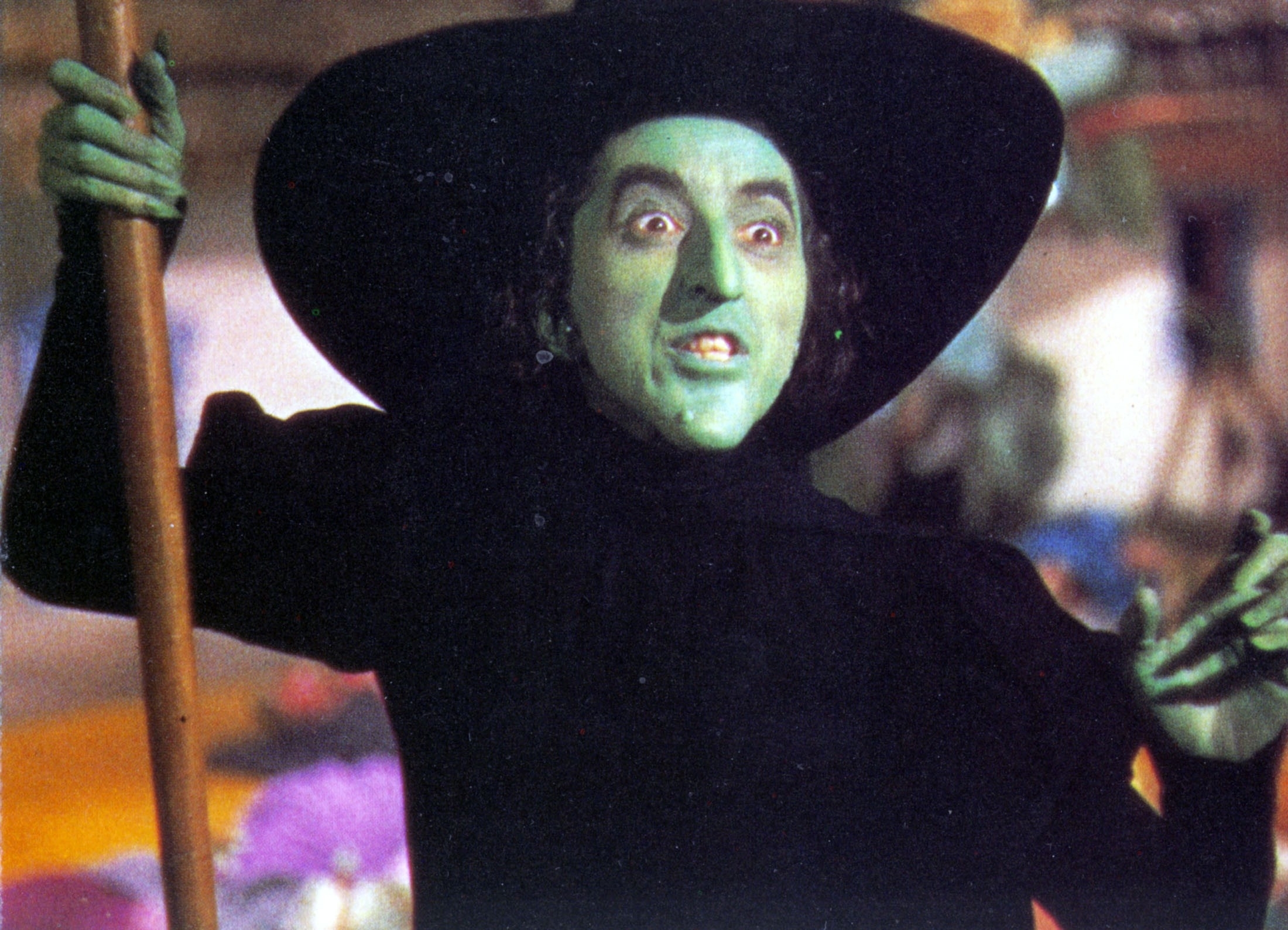 The Wicked Witch of the West holding a broom while wearing a black outfit and witch hat in &quot;The Wizard of Oz&quot;