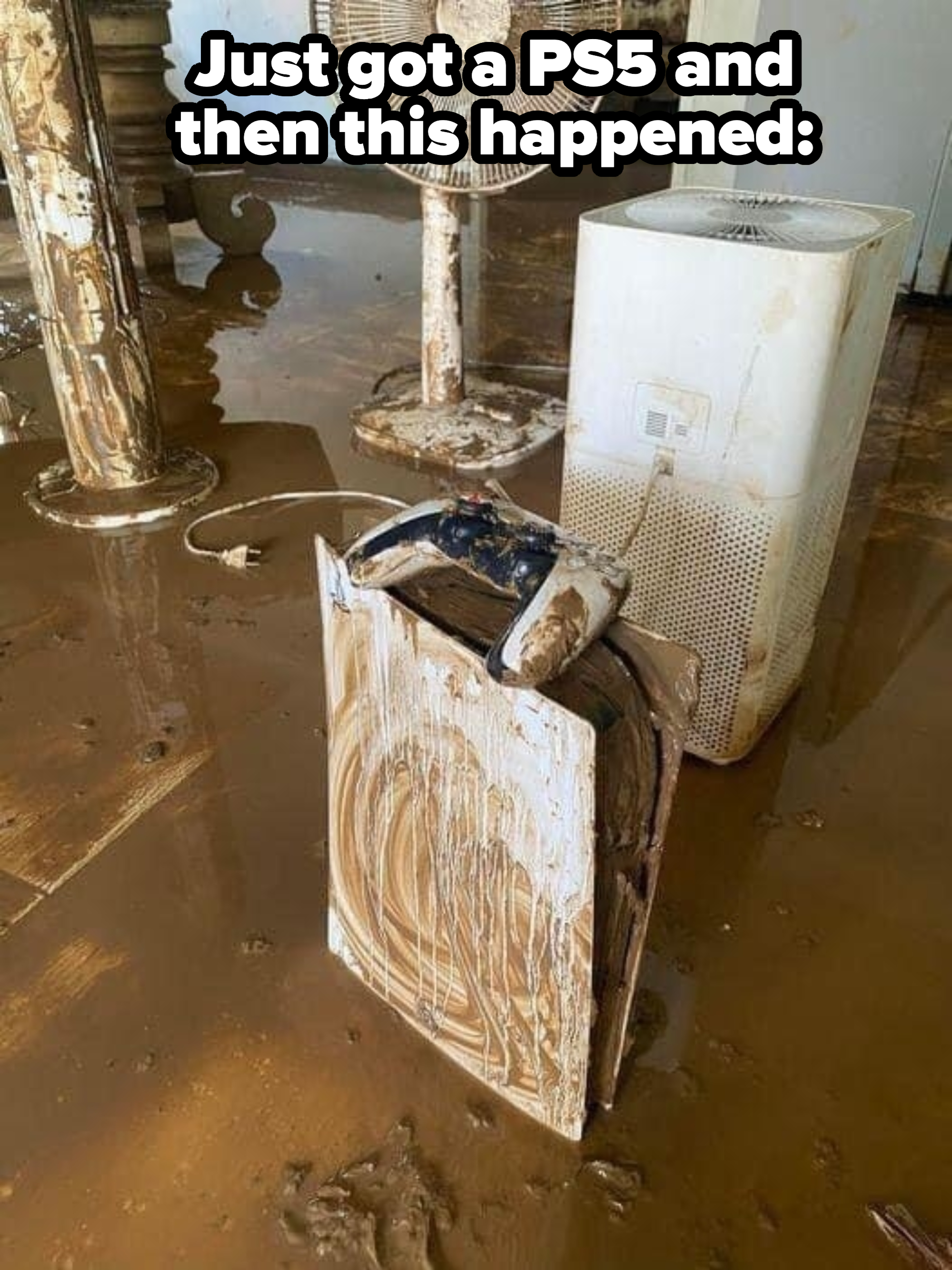 A mud-covered room with a fan, a humidifier, and an electric rice cooker. The floor and appliances are heavily soiled with mud