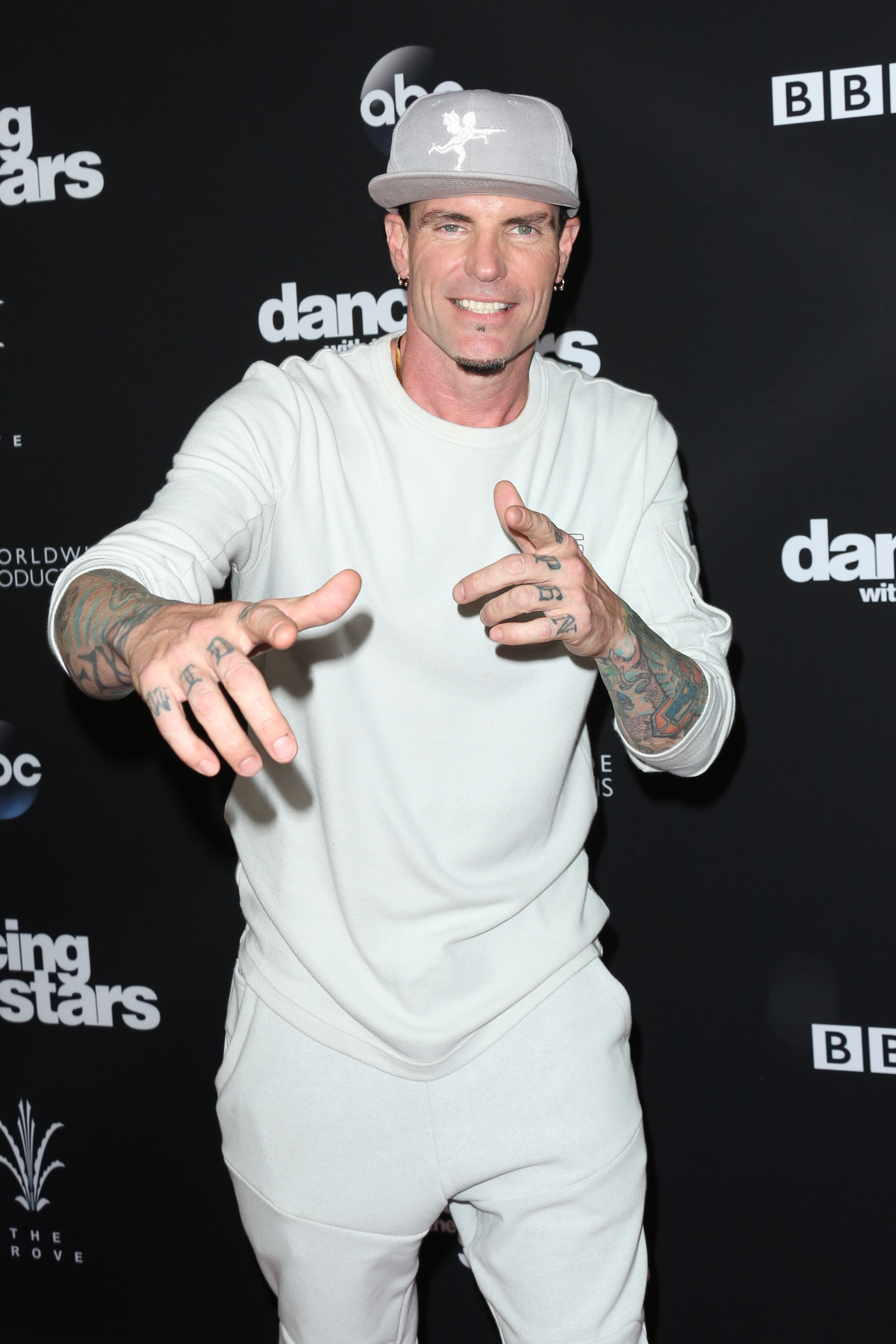 Vanilla Ice in a casual outfit with a cap, posing and pointing at the camera on the &quot;Dancing with the Stars&quot; red carpet