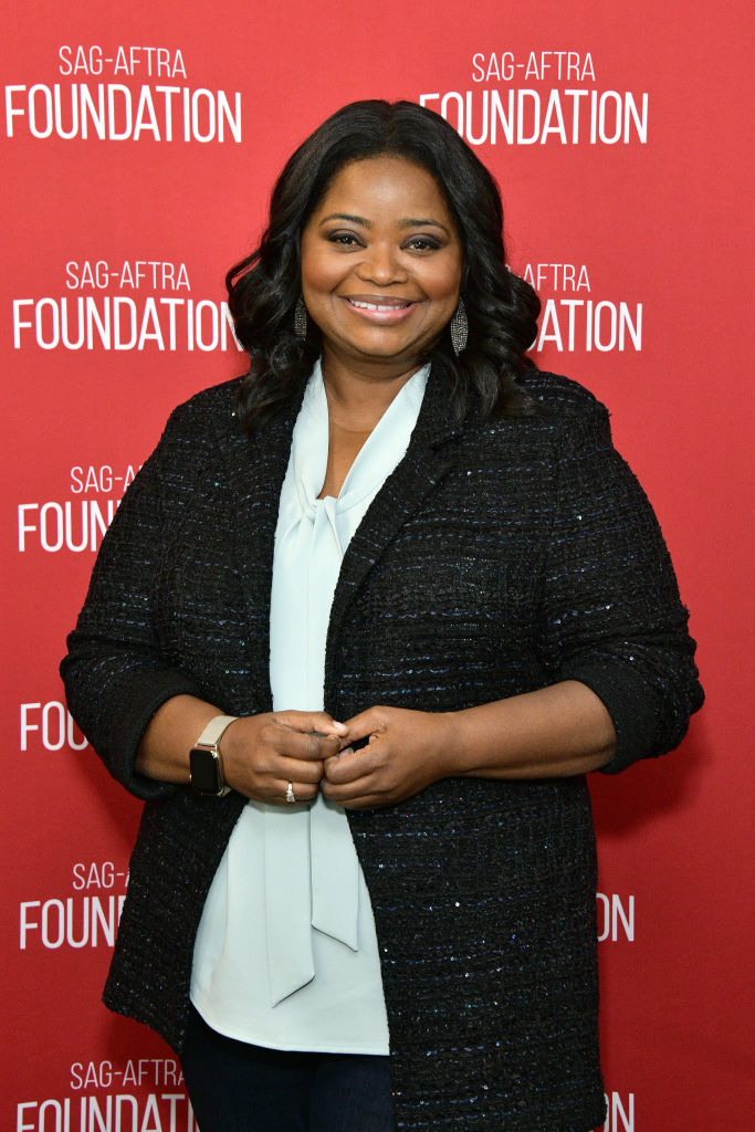 Octavia Spencer stands in front of a SAG-AFTRA Foundation backdrop, wearing a white blouse and a black sequined jacket. She is smiling and has her hands clasped