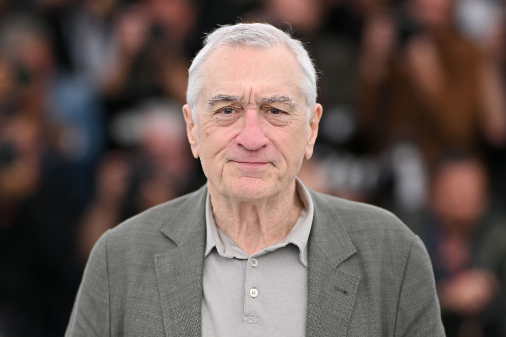 Robert De Niro, wearing a casual shirt and blazer, poses for photos at a public event