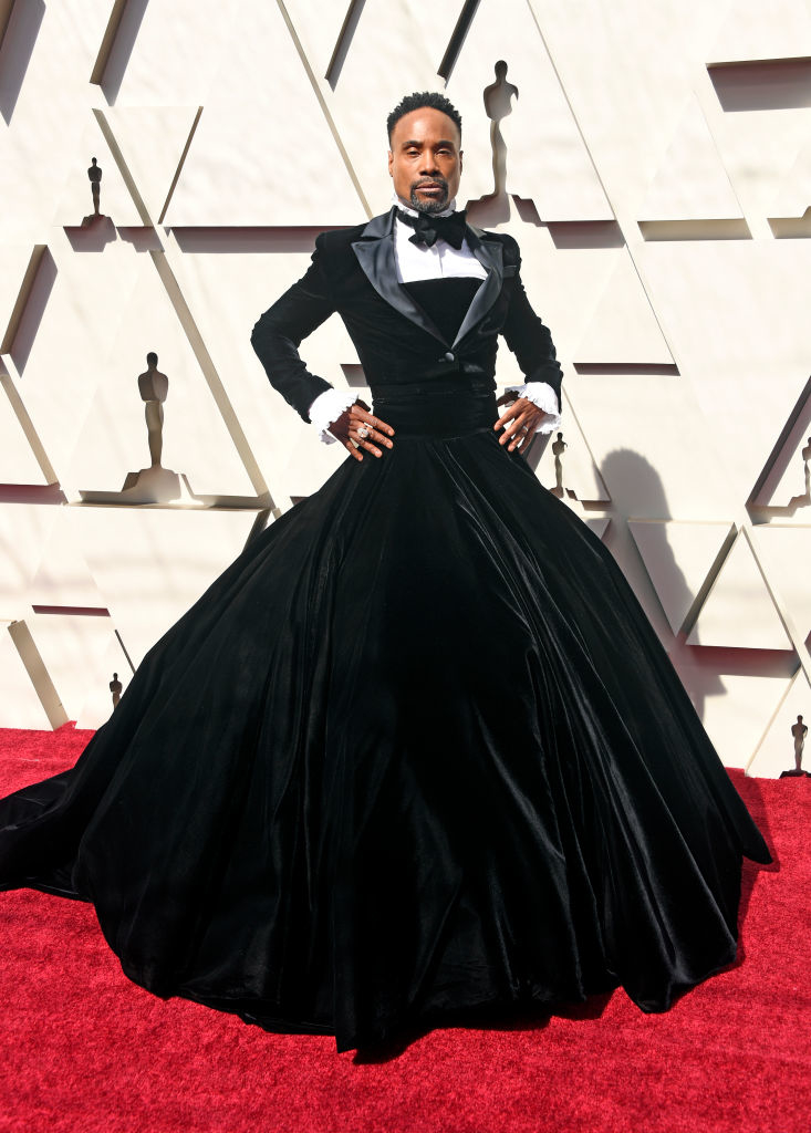 Billy Porter on the red carpet wearing a black velvet tuxedo gown with a full skirt