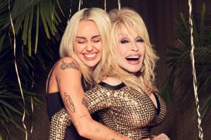 Miley Cyrus hugs Dolly Parton from behind. Miley smiles with closed eyes, showing tattoos on her arm. Dolly wears a stylish gold and black patterned dress