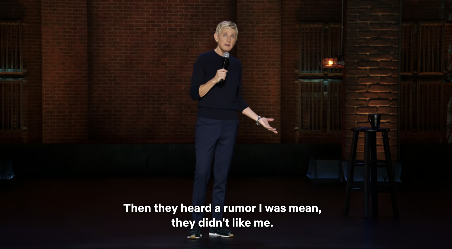 Ellen DeGeneres stands on stage holding a microphone. Caption on screen reads: &quot;Then they heard a rumor I was mean, they didn&#x27;t like me&quot;