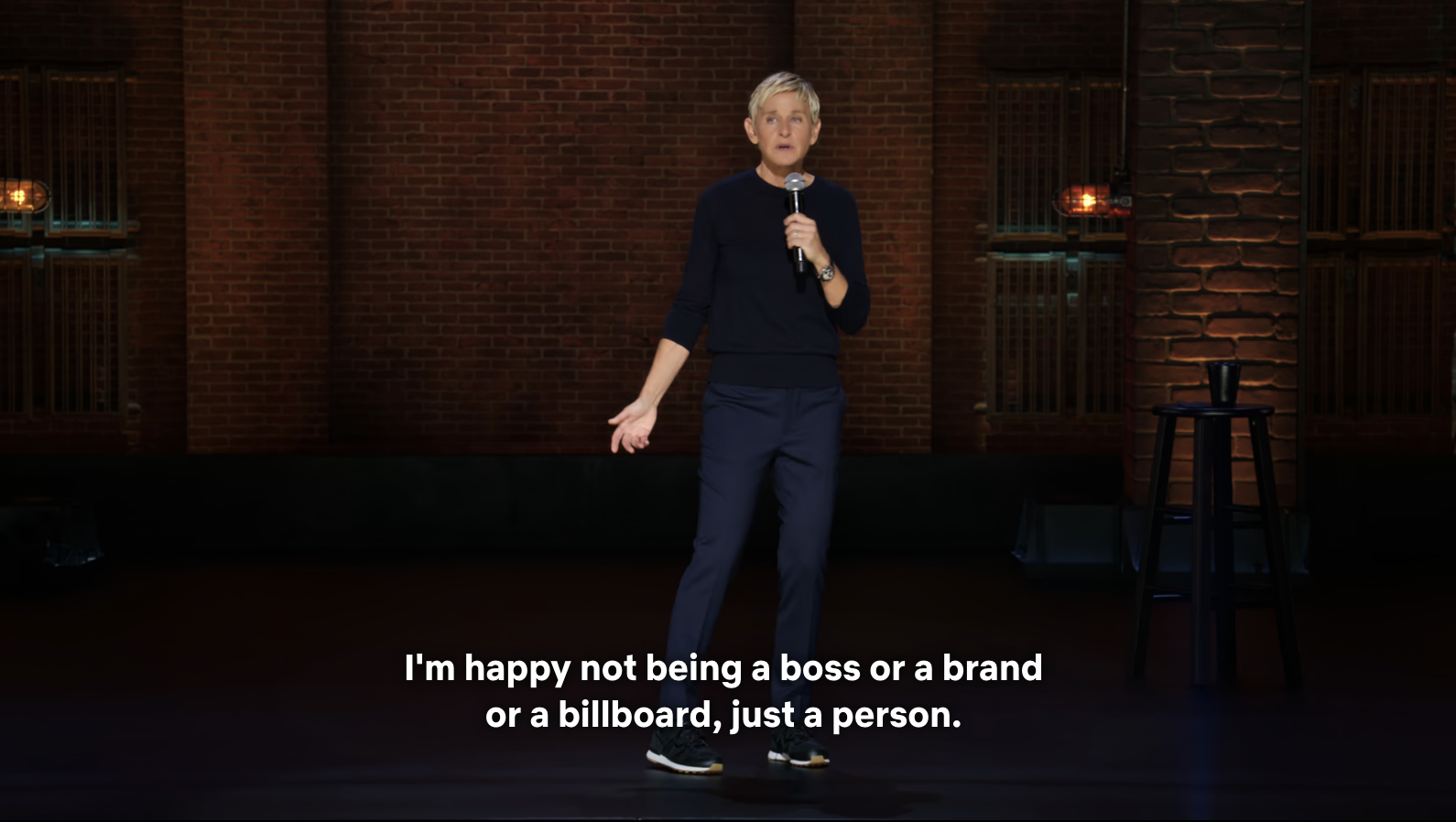 Ellen DeGeneres stands on stage with a microphone. Caption reads, &quot;I&#x27;m happy not being a boss or a brand or a billboard, just a person&quot;