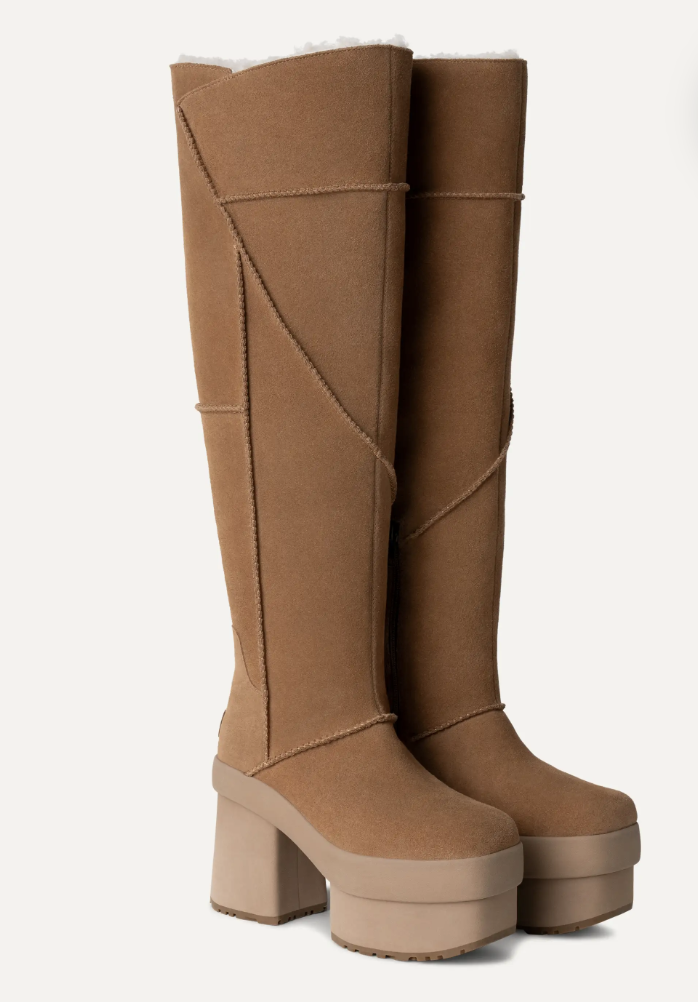 A pair of tall, tan suede boots with chunky platform heels and decorative stitching