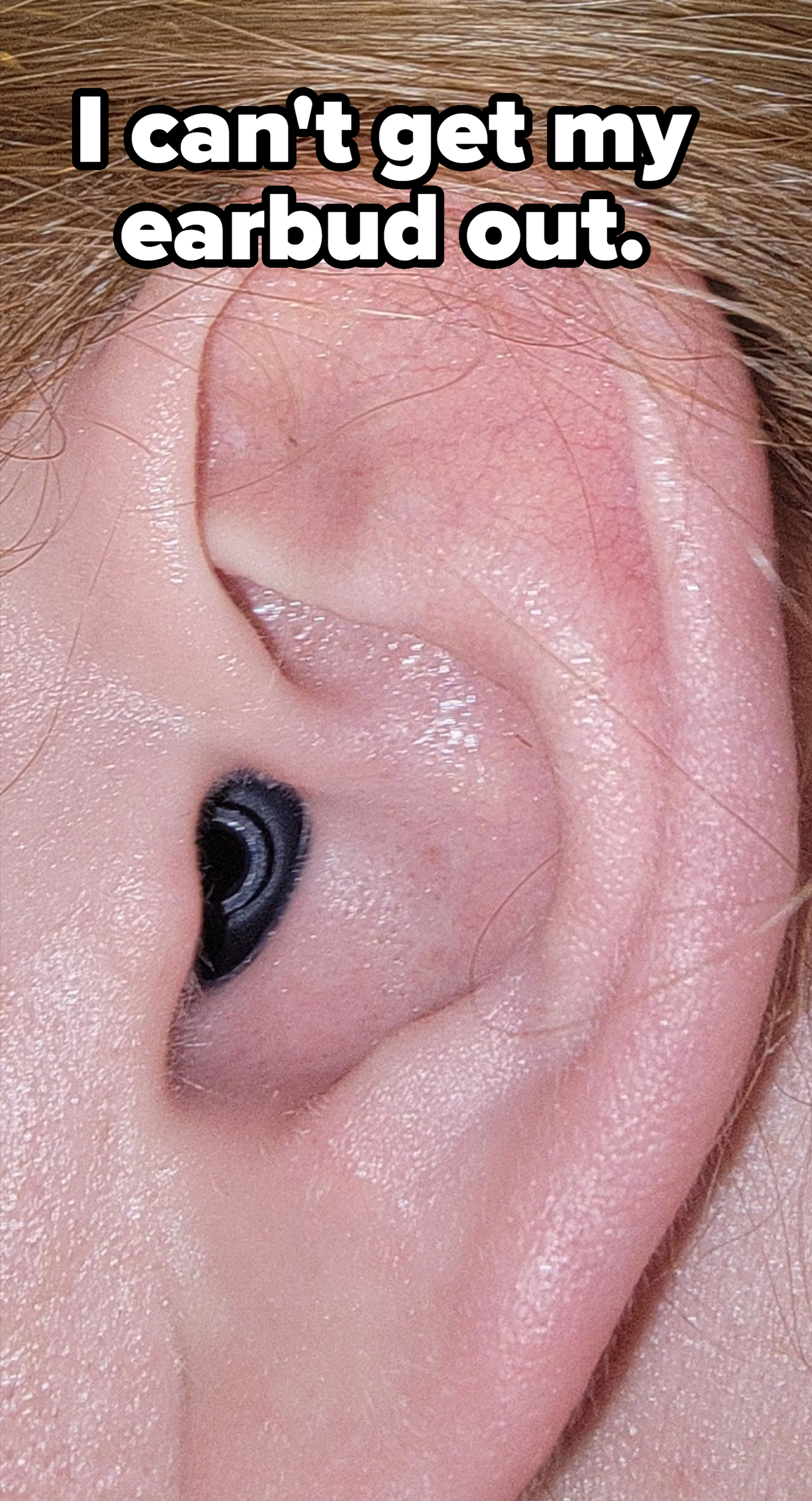 A close-up image of a human ear with a black in-ear hearing aid placed inside