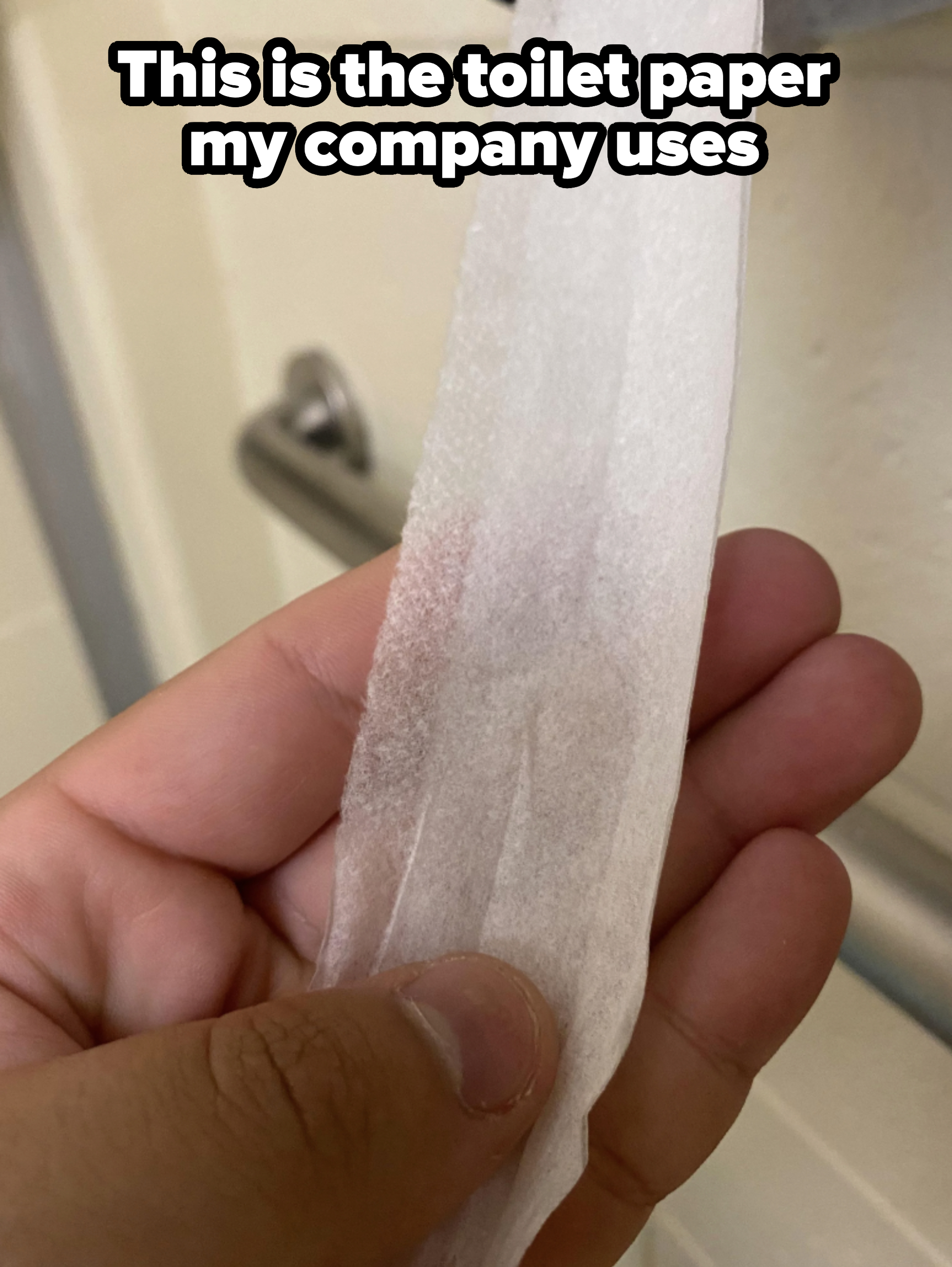 A hand holding a strip of what appears to be thin paper or fabric, possibly a cleaning wipe, next to a metal handrail