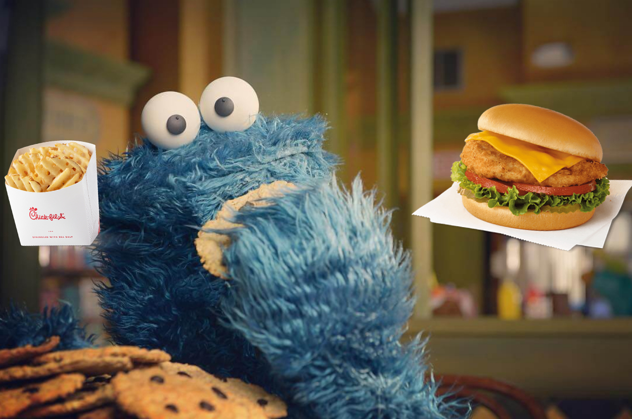 Cookie Monster from Sesame Street enjoys a cookie next to a Chick-fil-A box of waffle fries and a chicken sandwich