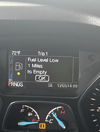 Car dashboard showing a 72°F temperature, Trip 1 details, fuel gauge warning &quot;Fuel Level Low&quot; with &quot;1 Miles to Empty,&quot; PRNDS indicator, and 120514 miles odometer