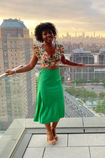 reviewer in a vibrant floral top and green skirt 