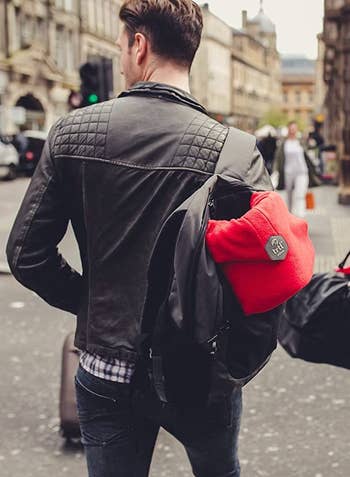 back of model with the red neck pillow attached to their backpack