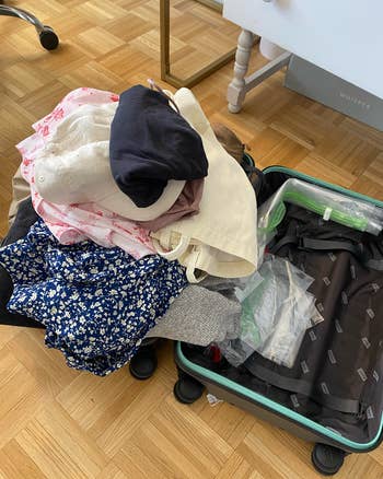 A suitcase spilling over with clothes 