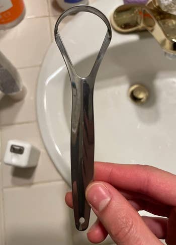 reviewer holding steel tongue scraper