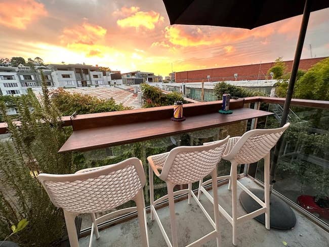 wooden bar on the rail of a balcony with three stools in front of it