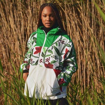 Person standing in tall grass wearing a floral print jacket