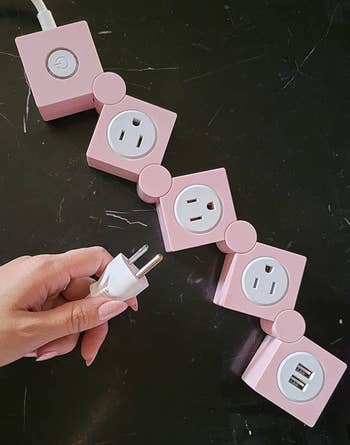 Multiple pink cube-shaped power adapters with one regular plug and USB ports
