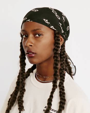 Woman with long braids wearing a headscarf and a chain necklace