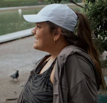 Model in a white baseball cap with a high ponytail coming out of the back  