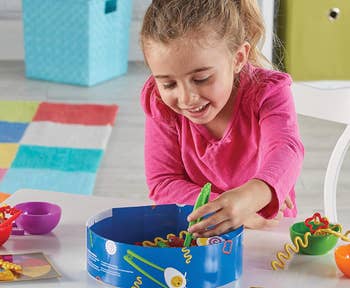 A young child happily playing with a colorful toy set at a table